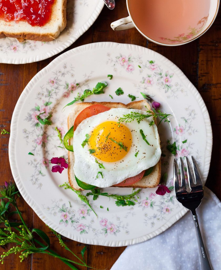 Floral place setting with an open faced sandwich served with tea. 