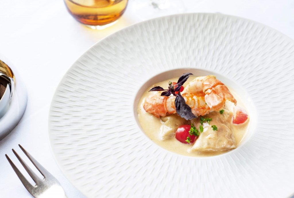 Delicious seafood in a rich cream sauce serve in a beautiful decorative white dish served at fine restaurant. 